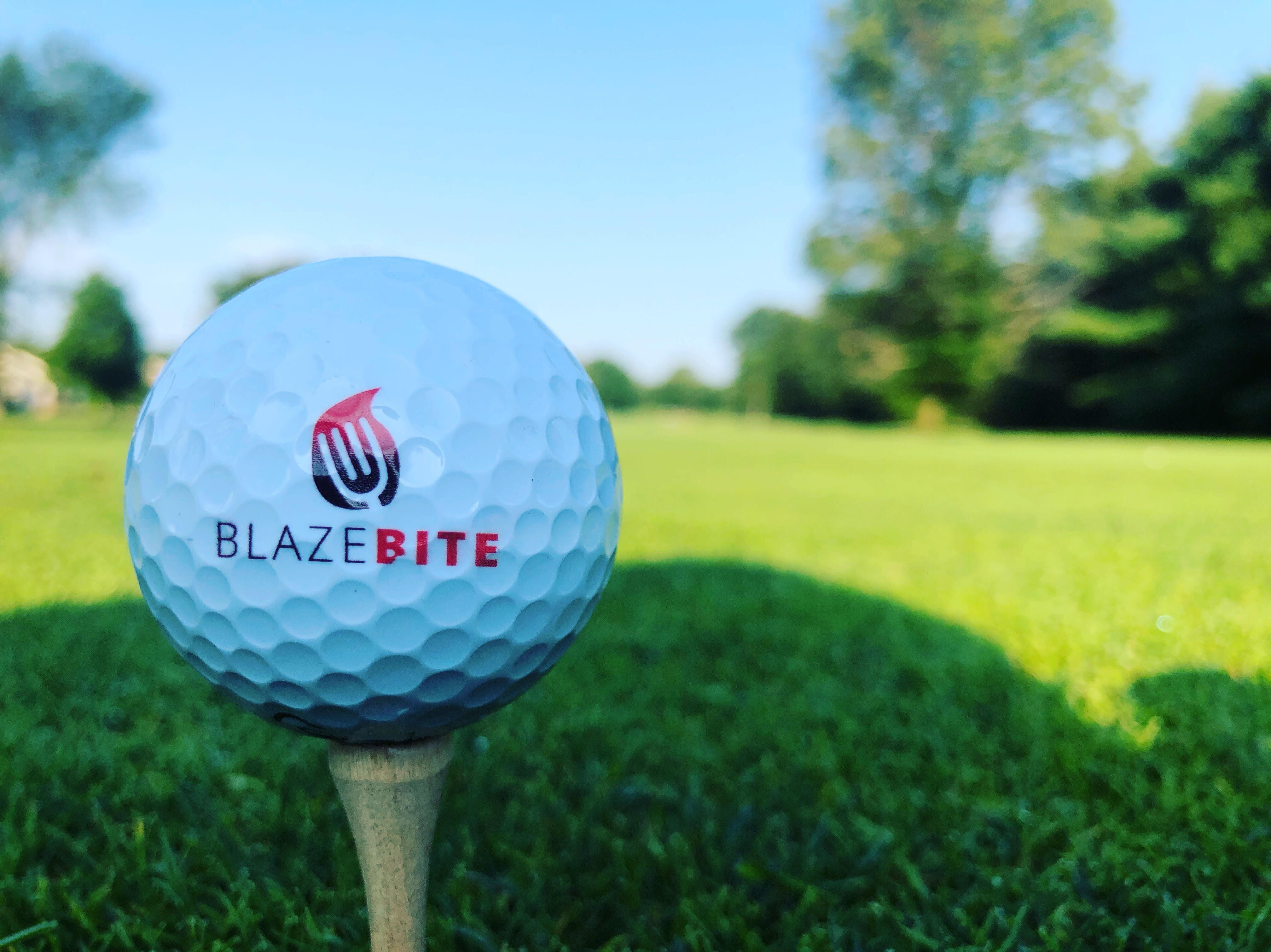 BlazeBite branded golf ball on a tee at a golf course