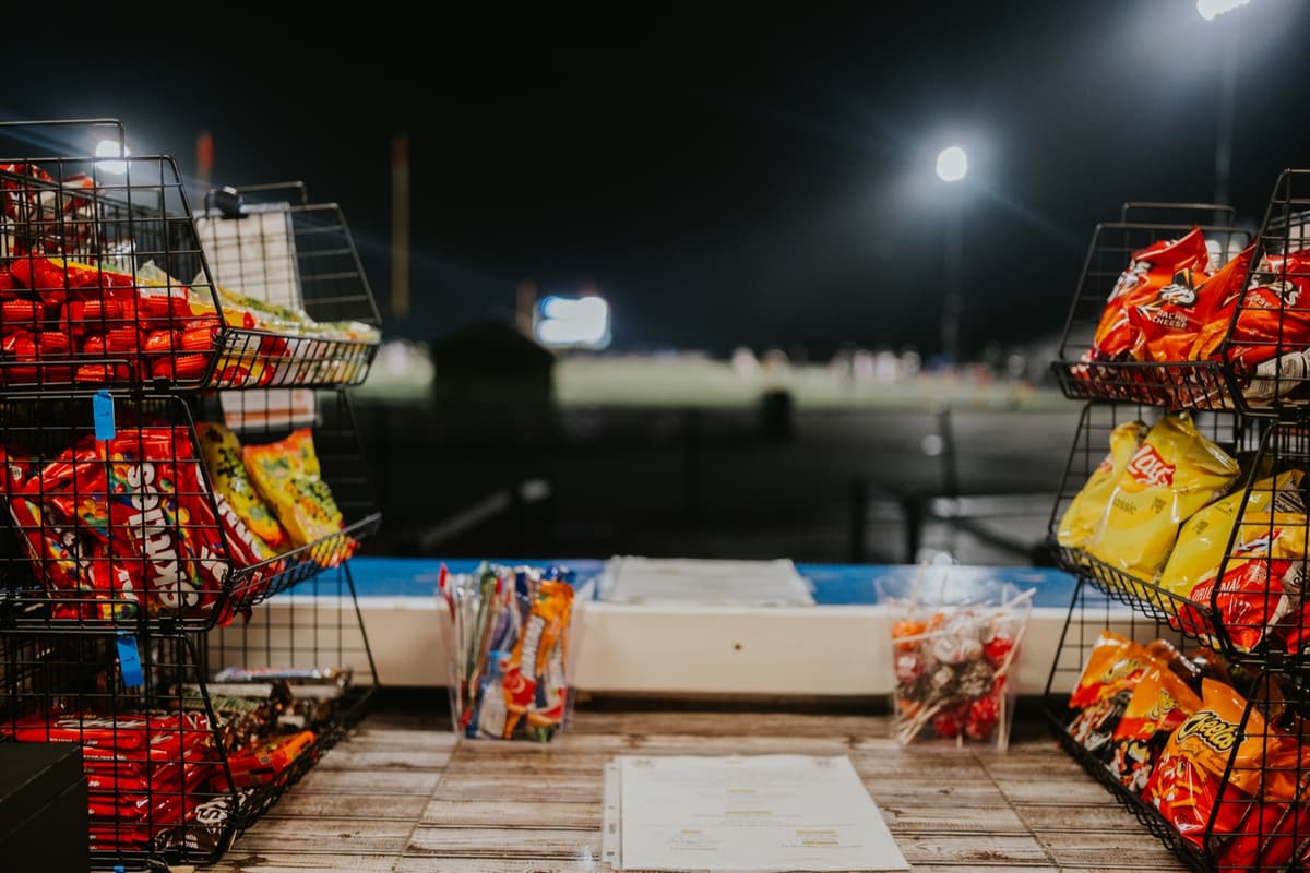 Racks of chips at the concession counter with the lit field behind them
