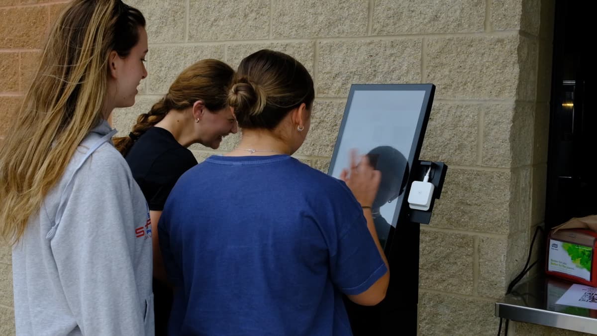 Three students ordering at a BlazeBite kiosk