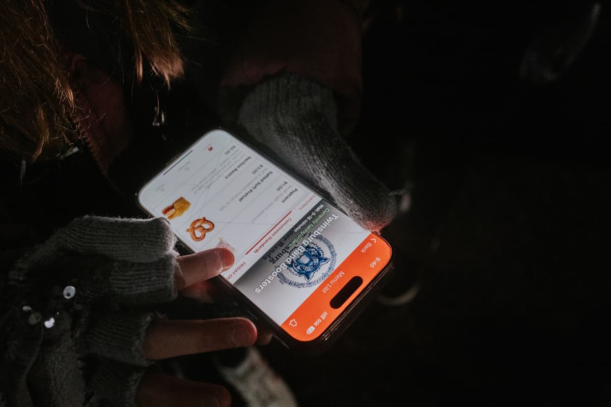 A hand holding a phone with a BlazeBite order at a night game
