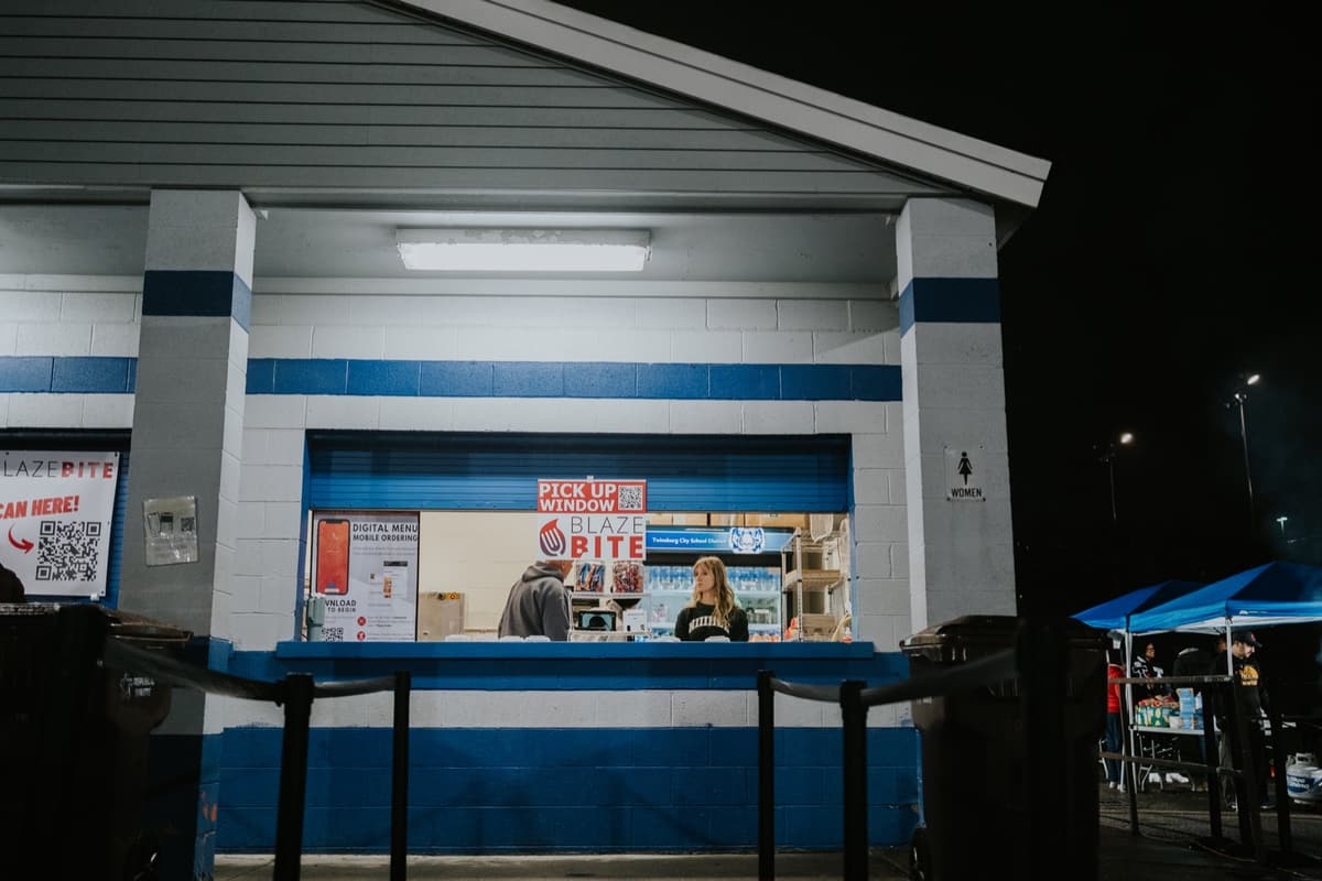 A worker at the BlazeBite pickup window at a school stand