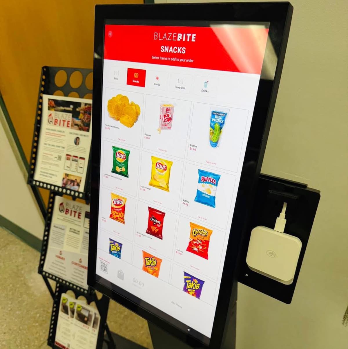 A BlazeBite screen showing a snacks menu of chips, candy, and drinks, with a card reader beside it