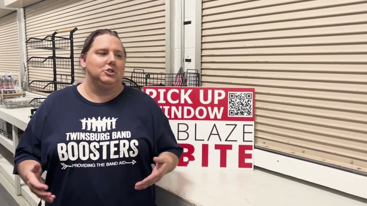 The Twinsburg Band Boosters president at the stand next to a BlazeBite pickup window sign