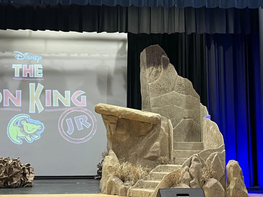 Large Pride Rock stage set with carved stone steps for a Lion King Jr. performance.